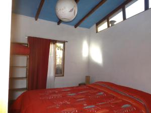 a bedroom with a bed with a red blanket and a window at Cabaña Canto del Viento, 4 personas in Horcon