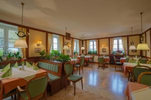 un comedor con mesas, sillas y ventanas en Hotel Post Leutkirch en Leutkirch im Allgäu