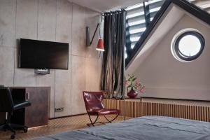 a bedroom with a bed and a tv and a chair at Hotel Monopol in Wrocław