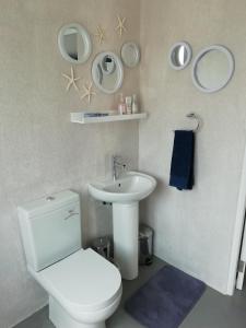 y baño con aseo blanco y lavamanos. en Shells Corner Cottage en Knysna