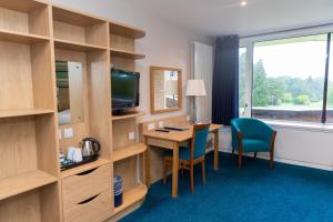 a hotel room with a desk and a television at Lilleshall House & Gardens and Lilleshall National Sports Centre in Telford