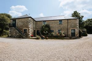 an old stone house with a gravel driveway at Goonwinnow Farm Cottages in Newquay