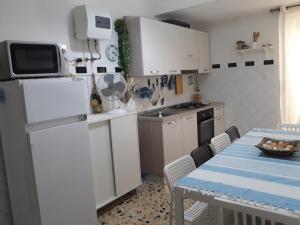una cucina con frigorifero bianco e tavolo con sedie di Vacanzasicilia a Porto Empedocle