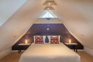 a attic bedroom with a bed with two lamps at Drentse krent in Veeningen