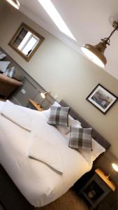 a bedroom with a large white bed with pillows at The Huntingdon in Dumfries