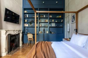 1 dormitorio con paredes azules, 1 cama y chimenea en Monsieur Didot, en Atenas