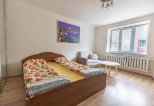 a bedroom with a bed and a chair and a window at Cozy Apartment In The City Center in Šiauliai