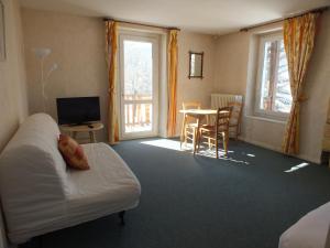 um quarto com uma cama e uma mesa com uma televisão em Hotel La Prairie em Méaudre