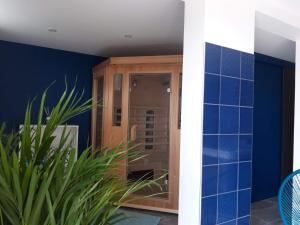 uma casa de banho com um chuveiro com paredes azuis e uma planta em L’Edaines em Bagnoles de l'Orne