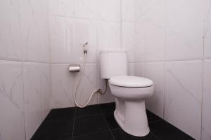 ein weißes WC im Bad mit einem Schlauch in der Unterkunft OYO 1506 Shabrina 2 Syariah in Solo