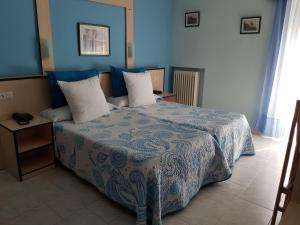 sypialnia z łóżkiem z niebieskimi ścianami i białymi poduszkami w obiekcie Hotel Fray Juán Gil w mieście Arévalo