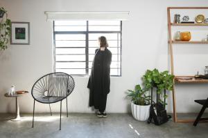 une femme en robe noire qui regarde par une fenêtre dans l'établissement Casa Nican by Barrio Mexico, à Guadalajara