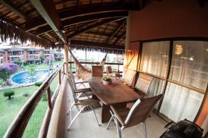 weranda z drewnianym stołem i krzesłami na balkonie w obiekcie Cumbuco Dream Village w mieście Cumbuco