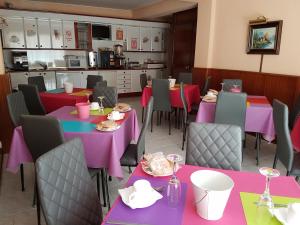 a restaurant with tables and chairs with pink and purple tables at Hotel Fray Juán Gil in Arévalo