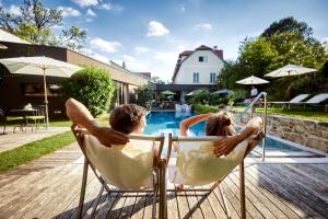 un hombre y una mujer sentados en una silla junto a una piscina en Hotel Landhaus Moserhof, en Gumpoldskirchen