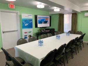 a conference room with a table and chairs and a screen at Midtown Motel & Suites in Moncton