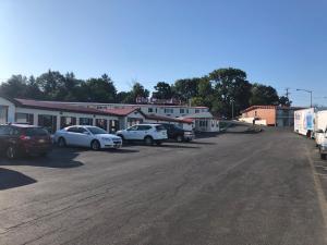 a parking lot with cars parked in front of a building at Red Carpet Inn Syracuse Airport in North Syracuse