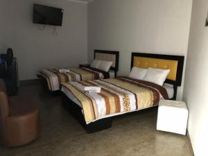 two beds in a room with a tv and a chair at Bella Durmiente Hotel & Eventos in Chincha Alta