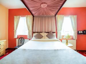 a bedroom with a large bed with red walls and windows at OYO The Royal Hotel in Newcastle upon Tyne
