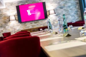 a room with a table with a tv and chairs at Villa Augeval Hôtel de charme & Spa in Deauville