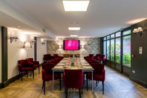 a dining room with a long table and red chairs at Villa Augeval Hôtel de charme & Spa in Deauville