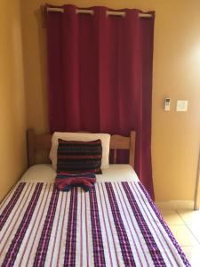 a bedroom with a bed with a red curtain at Ambergris Sunset Hotel in San Pedro