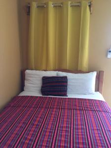 Ambergris Sunset Hotel في سان بيدرو: سرير مع بطانية ملونة فوقه