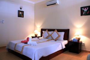 a bedroom with a bed with white sheets and two lamps at Tien Dat Resort in Mui Ne