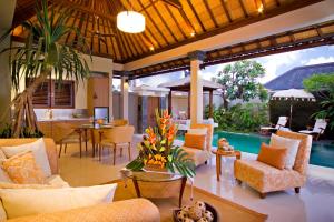 ein Wohnzimmer mit Stühlen, einem Tisch und einem Pool in der Unterkunft DISINI Luxury Spa Villas-CHSE Certified in Seminyak