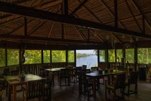 a restaurant with tables and chairs and a view of a river at Dolphin Lodge in Careiro