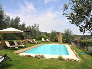 uma piscina num quintal com cadeiras e um guarda-sol em Villa Agrirosa em Monte San Savino