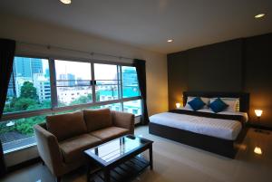 a bedroom with a bed and a couch and a window at Baan Mina in Bangkok