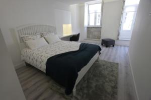 a bedroom with a bed and a desk and two windows at Apartamento das Malheiras in Viana do Castelo