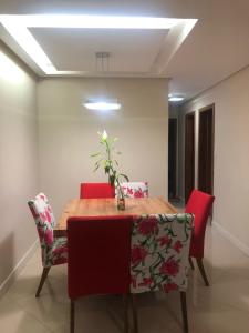 a dining room table with red chairs and a plant on it at Propriedade aconchego de família in Salvador