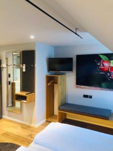 a room with a bed and a tv on a wall at Hotel Waldvogel in Leipheim
