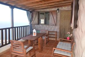 porche con mesa de madera y sillas en el balcón en Terraza del Atlántico en Playa de Santiago