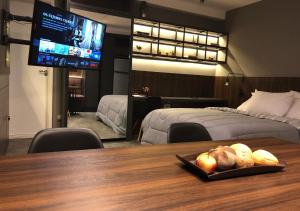 uma sala com uma mesa com uma televisão e um quarto em Apartamento super bem decorado em frente ao shopping em Curitiba