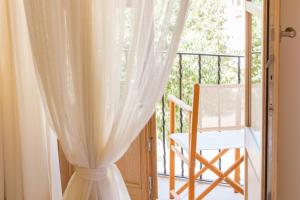 a window with a white curtain and a chair on a balcony at Fonda Llabres Boutique in Alcudia