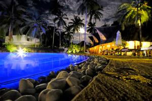 a swimming pool with rocks next to a resort at night at Pongwe Bay Resort in Pongwe