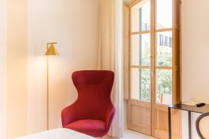 a red chair in a room with a window at Fonda Llabres Boutique in Alcudia