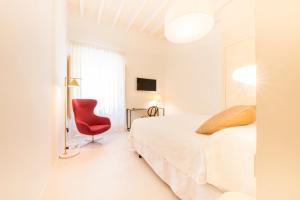 a white room with a bed and a red chair at Fonda Llabres Boutique in Alcudia