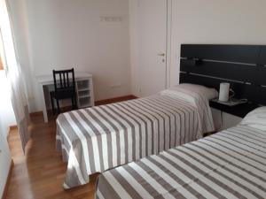 2 camas en una habitación con mesa y silla en al 106 en Trieste