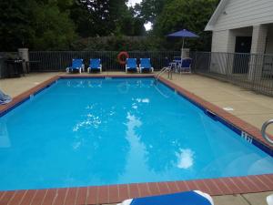 a large swimming pool with blue chairs and an umbrella at InTown Suites Extended Stay Auburn AL in Auburn