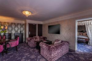 a living room with pink furniture and a television at Clontarf Castle Hotel in Dublin