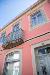 a pink building with a balcony and two windows at Apartamentos Castelo in Póvoa de Varzim