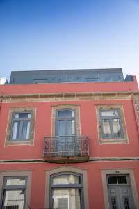 a red building with three windows and a balcony at Apartamentos Castelo in Póvoa de Varzim