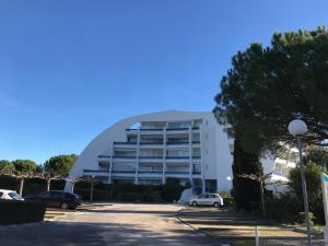 a large white building with cars parked in a parking lot at Appartement classé, vue mer, clim, wifi, parking in La Grande-Motte