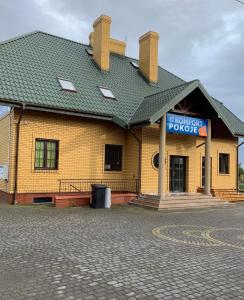 a yellow building with a sign in front of it at Pokoje Komfort in Szypliszki