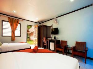 ein Schlafzimmer mit zwei Betten und einem Schreibtisch und einem Fernseher in der Unterkunft Lanta Coral Beach Resort in Ko Lanta