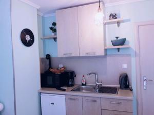 uma cozinha com armários brancos e um lavatório em Manina Superior Studios em Tessalónica